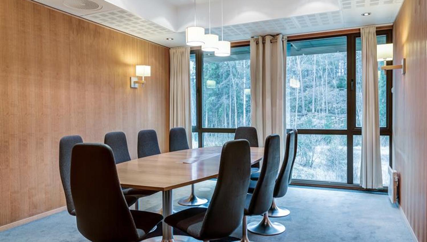 Elegant styrerom med rundt bord, komfortable stoler og utsikt mot grÞntomrÄde