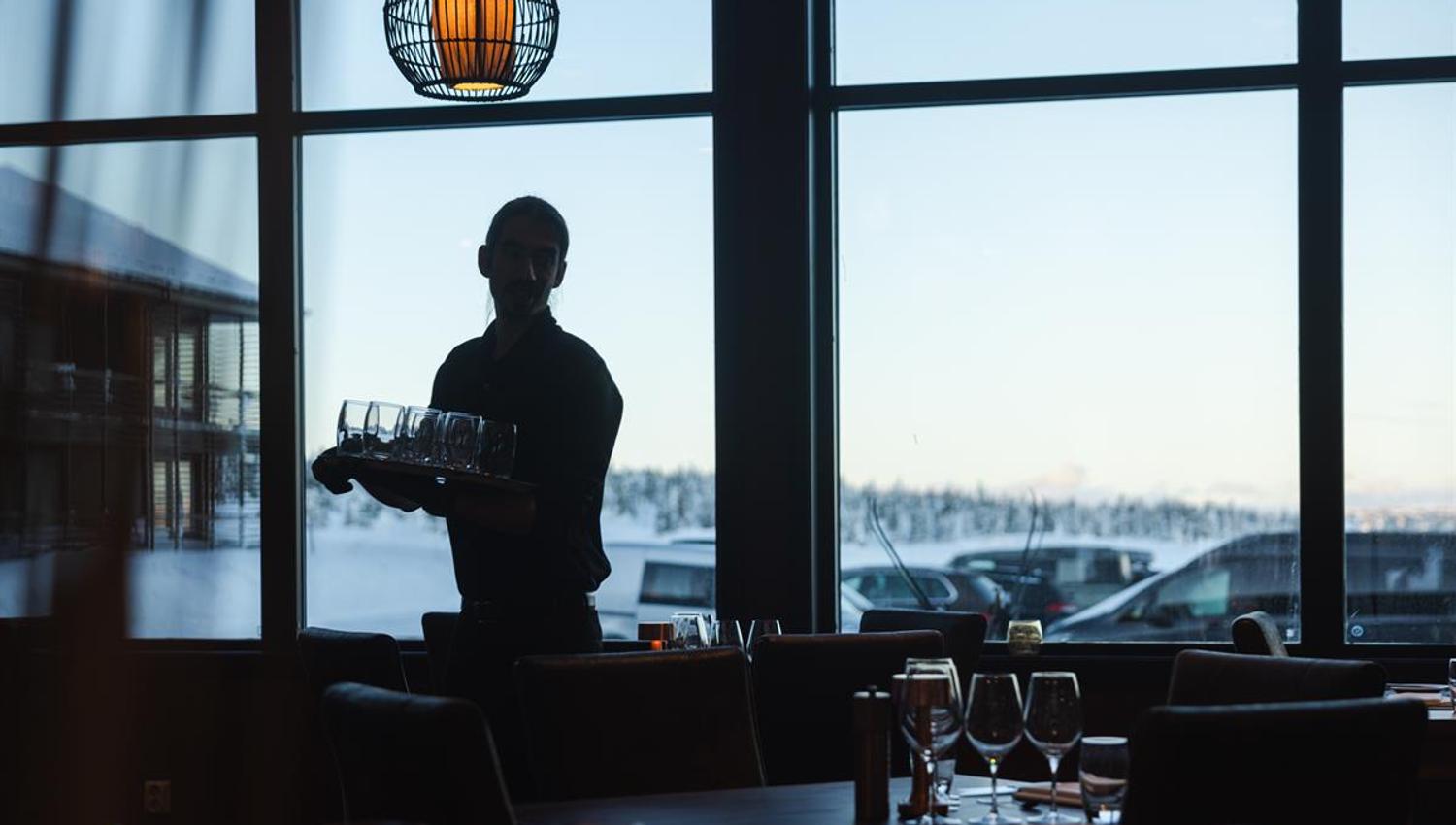 Servering i restaurant med utsikt mot store vinduer.