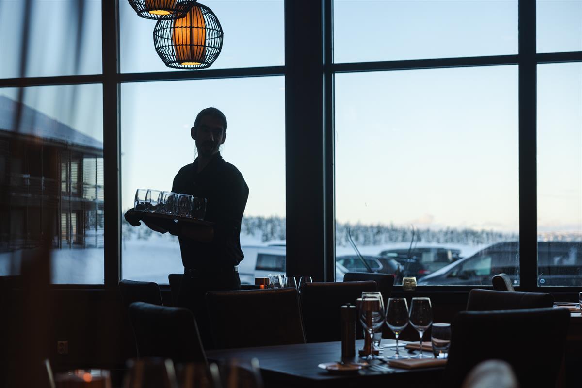 Servering i restaurant med utsikt mot store vinduer.