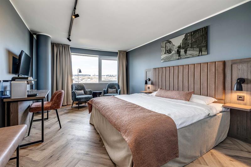 Hotellrom med dobbeltseng, skrivebord, to lenestoler og flott utsikt