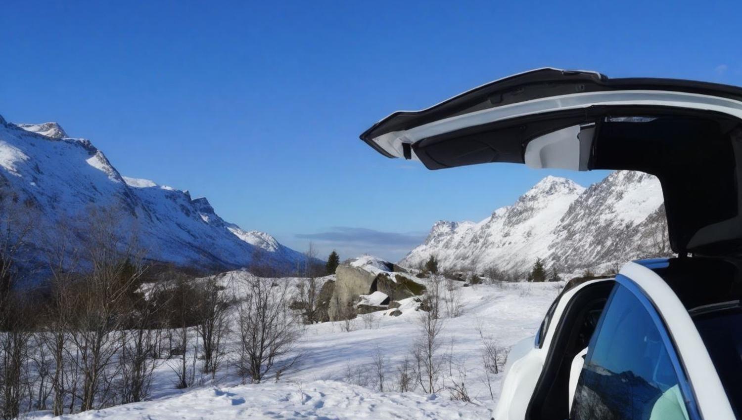 A Tesla with an open door and views of the surrounding landscape