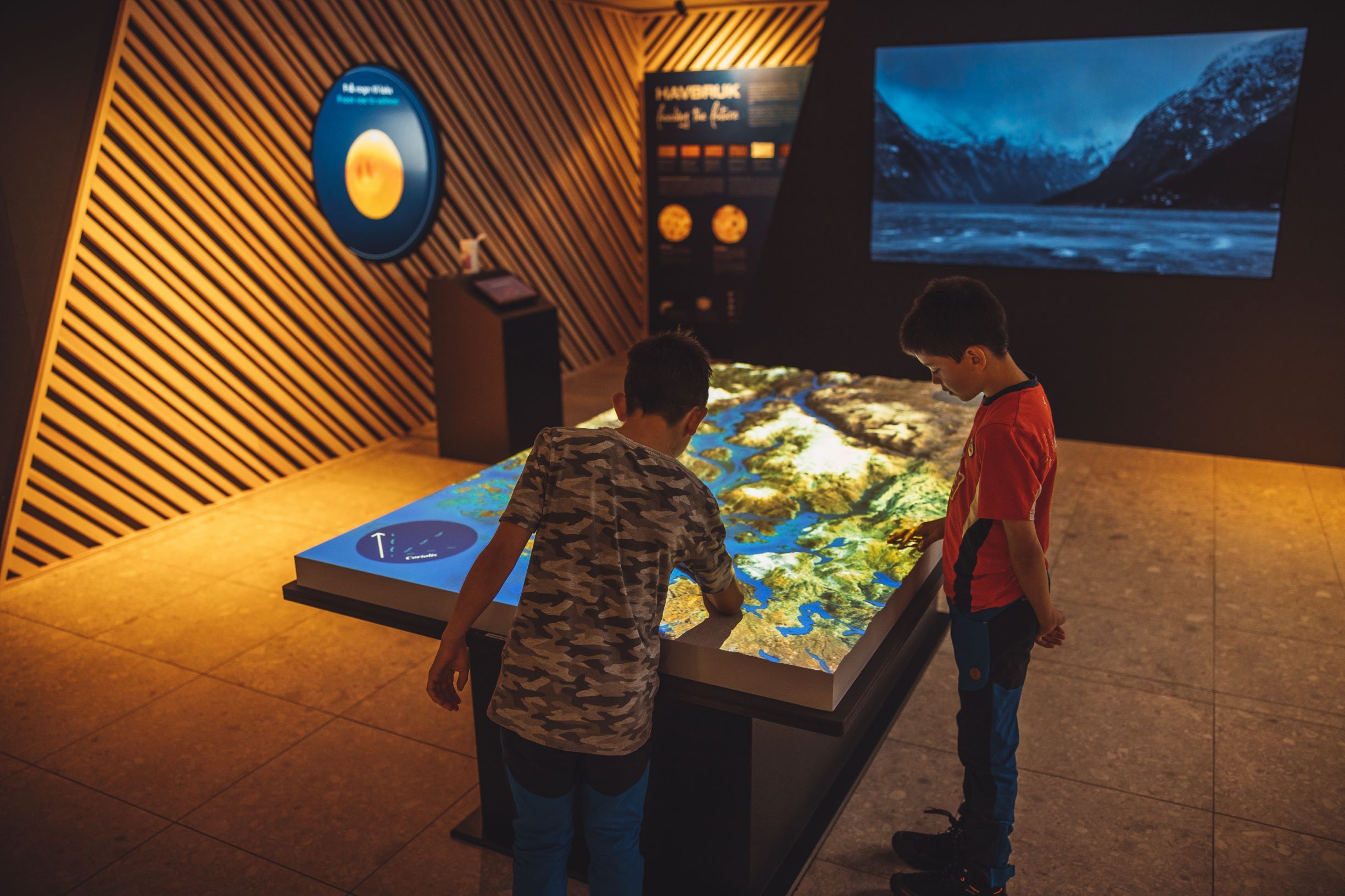 Children exploring the interactive landscape table in the “This is where we live” exhibition at the Hardanger Aquaculture Centre.