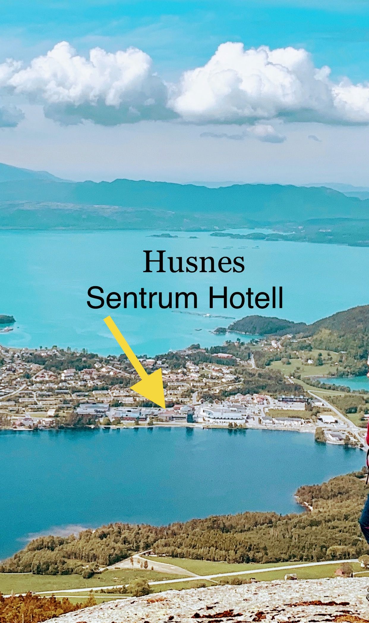 Dronebilete av Husnes Sentrum med plassering av Husnes Sentrum Hotell, omkransa av vakker natur og fjordutsikt.