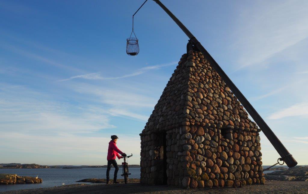 One with a bicycle by the tilting lighthouse at Verdens Ende