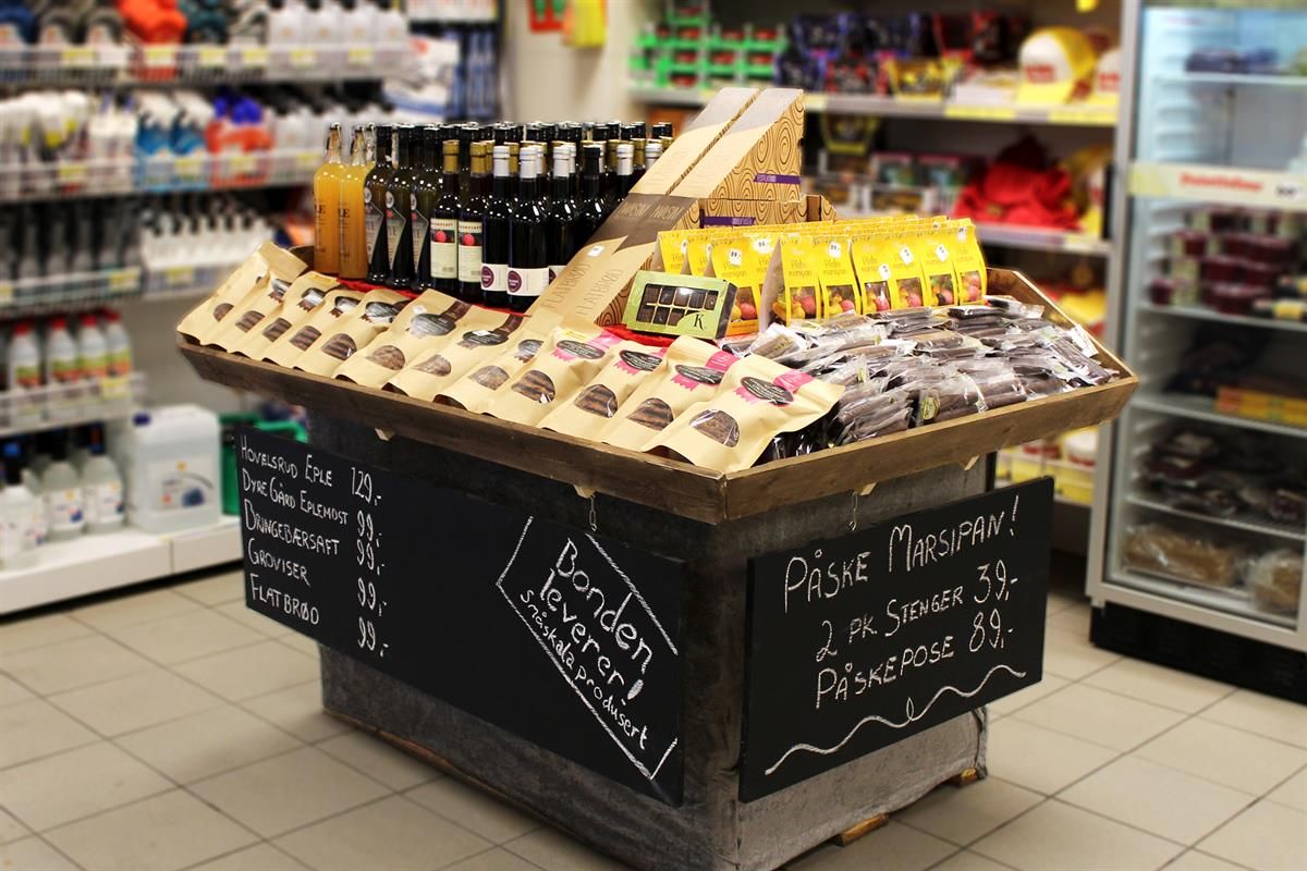 A store display island featuring an assortment of beverages and snacks, with handwritten chalkboard-style information on the sides.