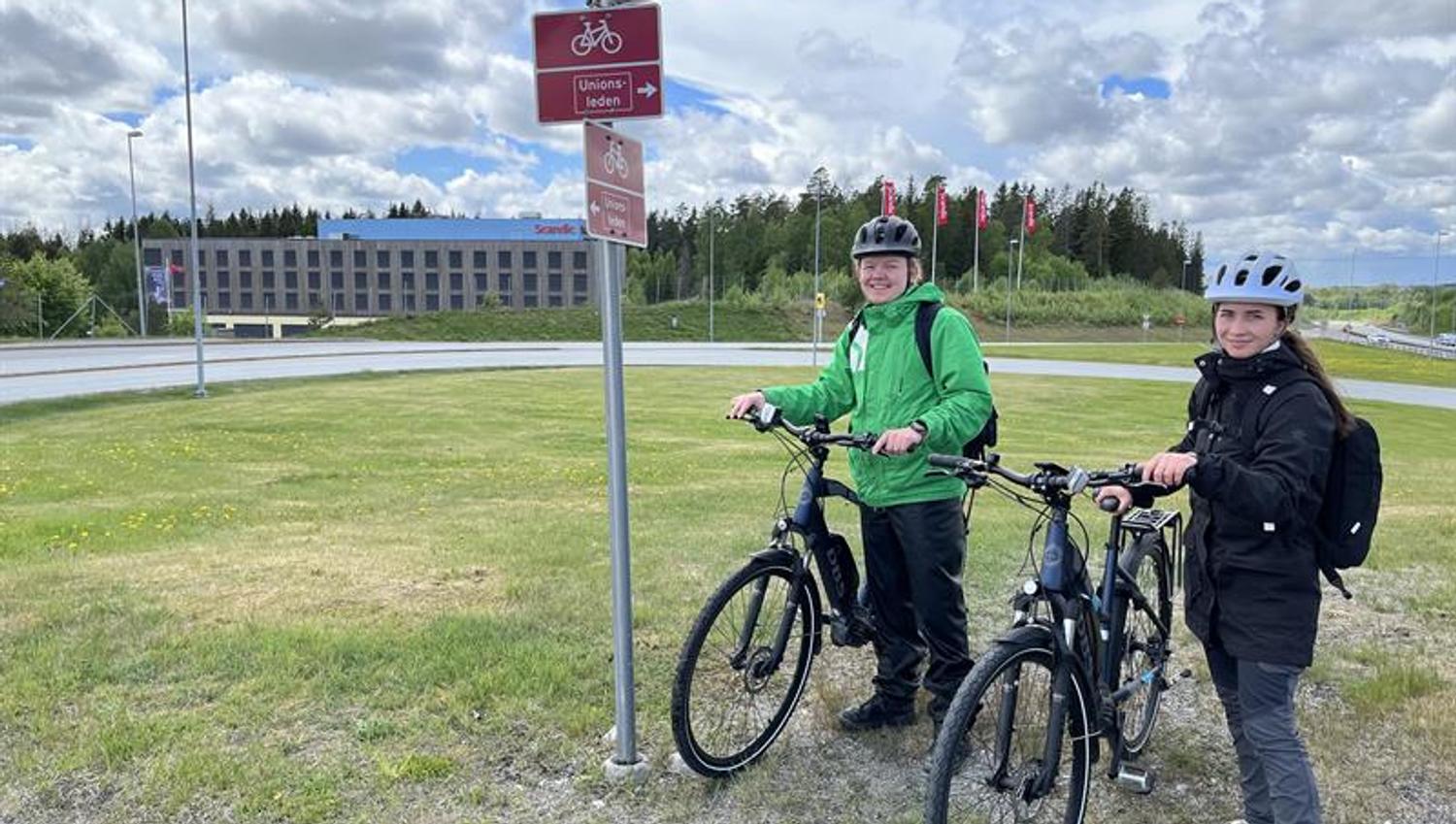 Syklister står ved stolpe