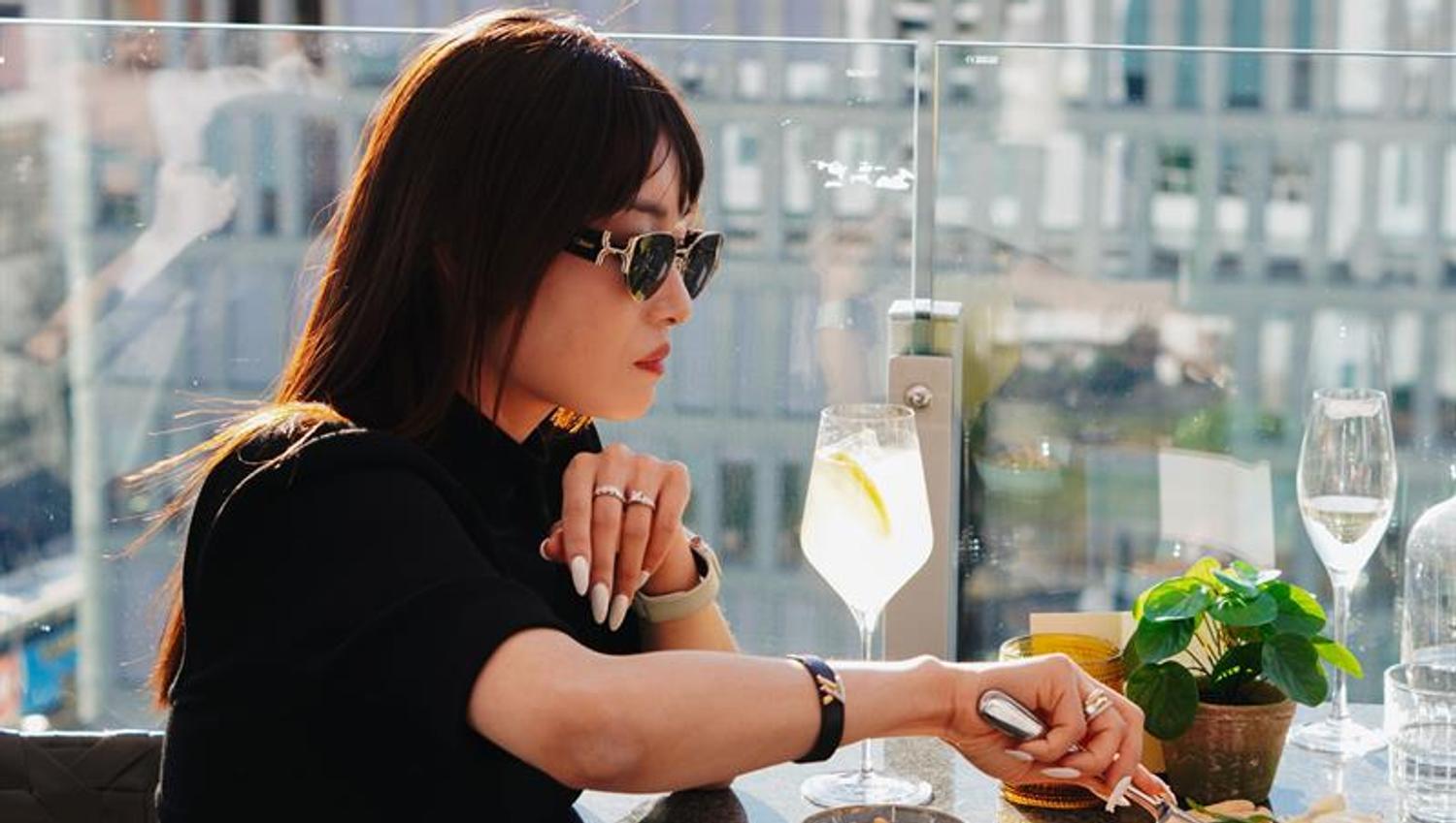 Woman enjoying food and drinks in the evening sun on a rooftop terrace in Oslo.