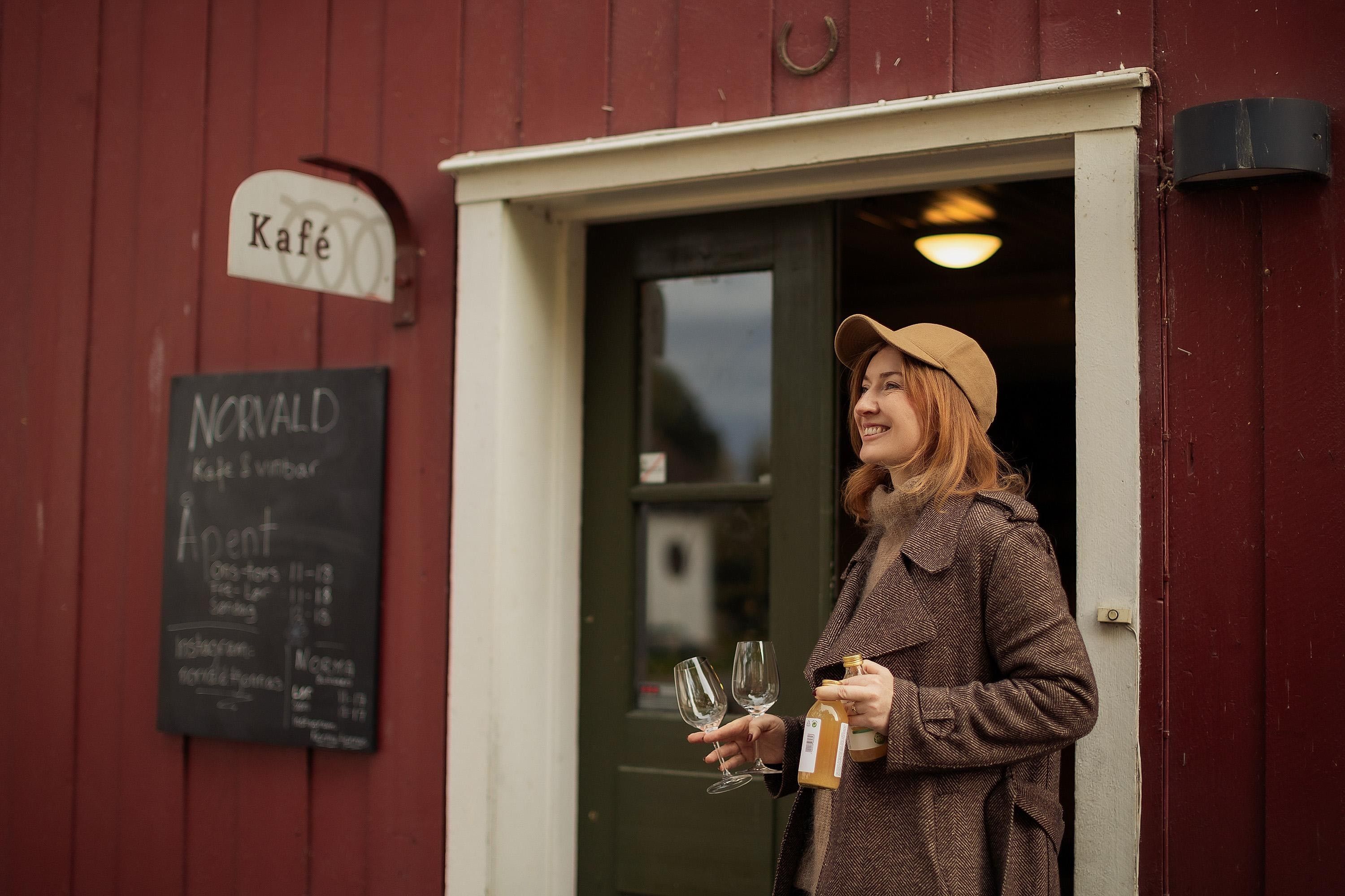 Norvald kafe og vinhus på Gjøvik Gård. Gjest utenfor døren med eplemost.