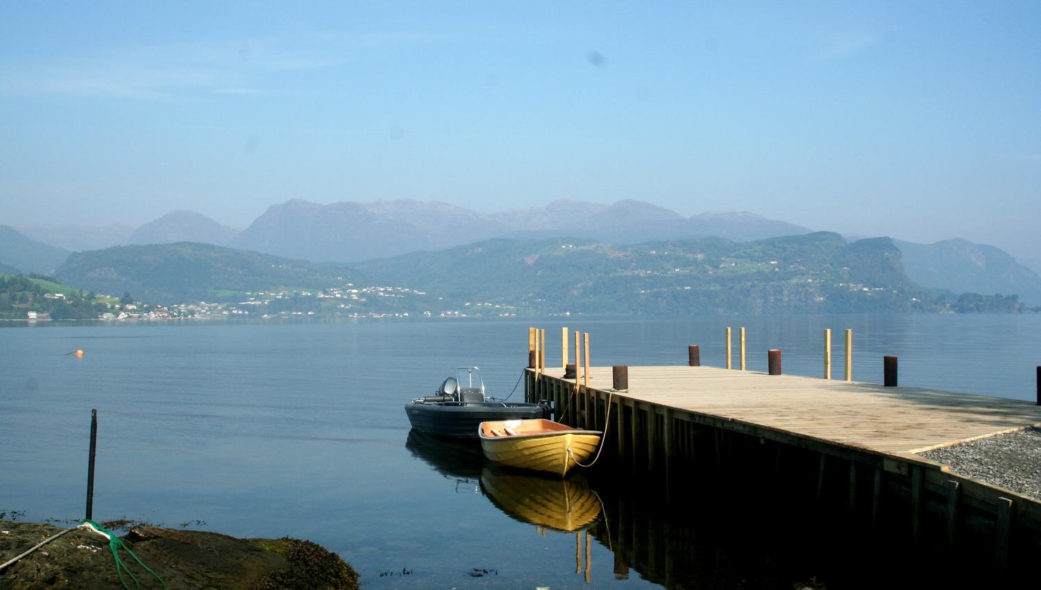 Pier and boats at Oddland Camping with views of the mountains and fjord landscape in Hardanger.
