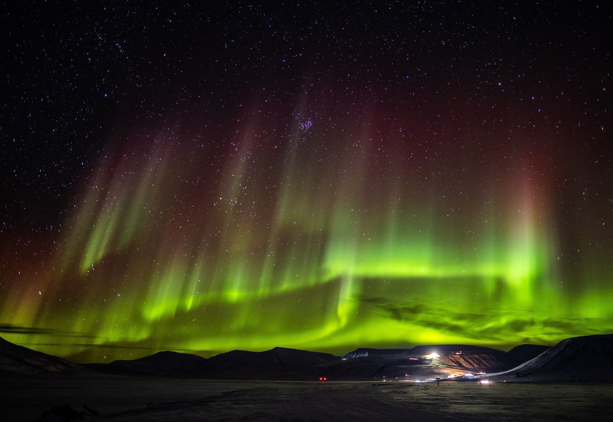 Northern lights shining in the skies above an open valley
