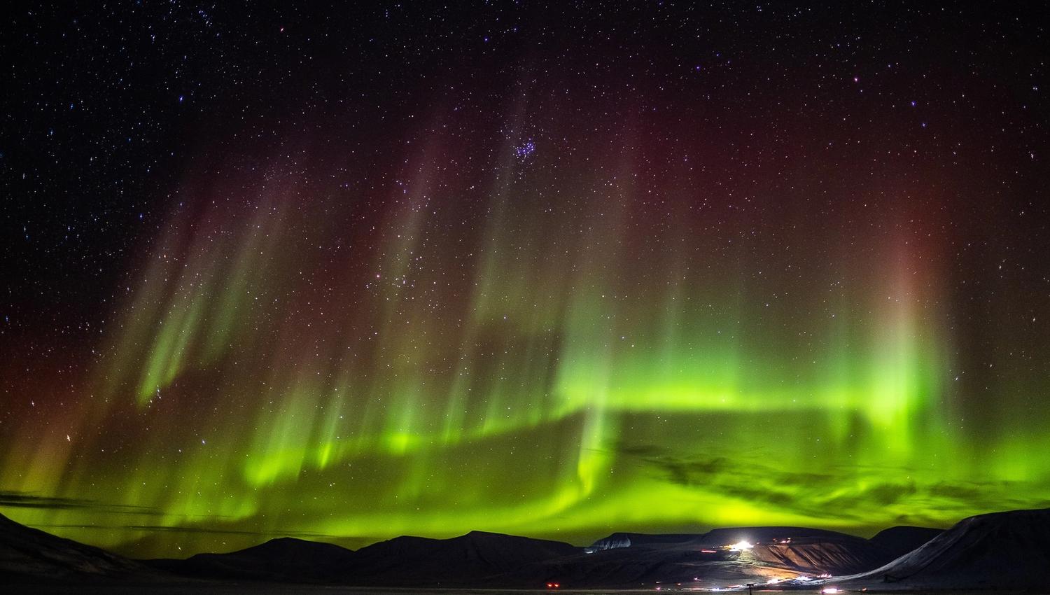 Northern lights shining in the skies above an open valley