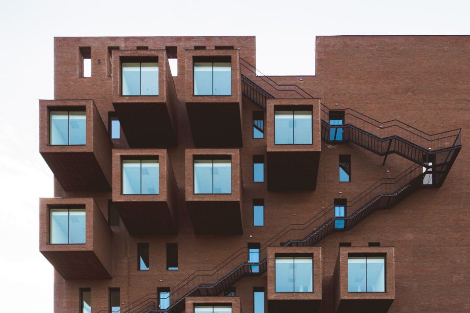 Brown building with outside stairs and large windows.