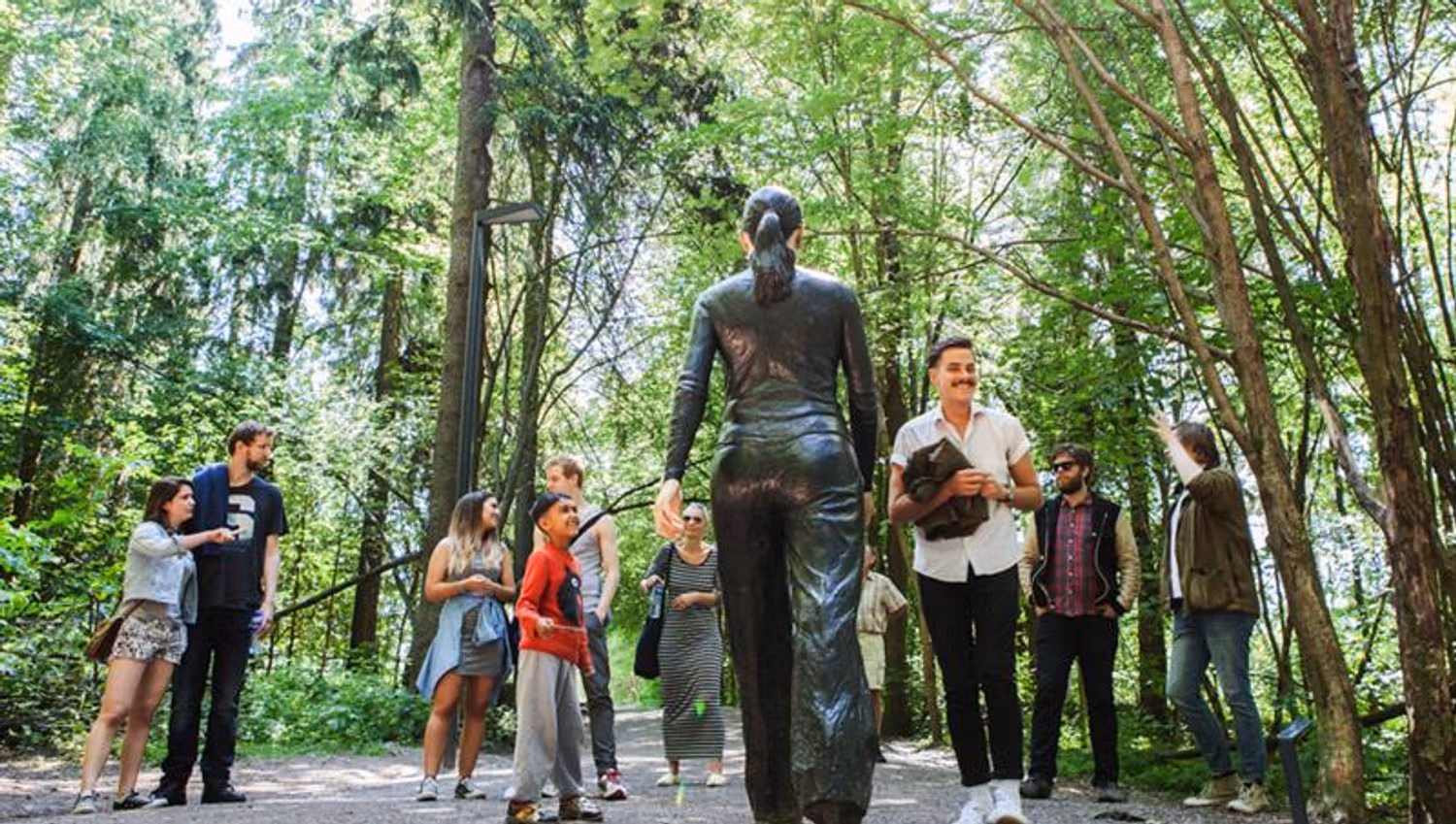 People standing in front the of the sculpture "Walking Woman".