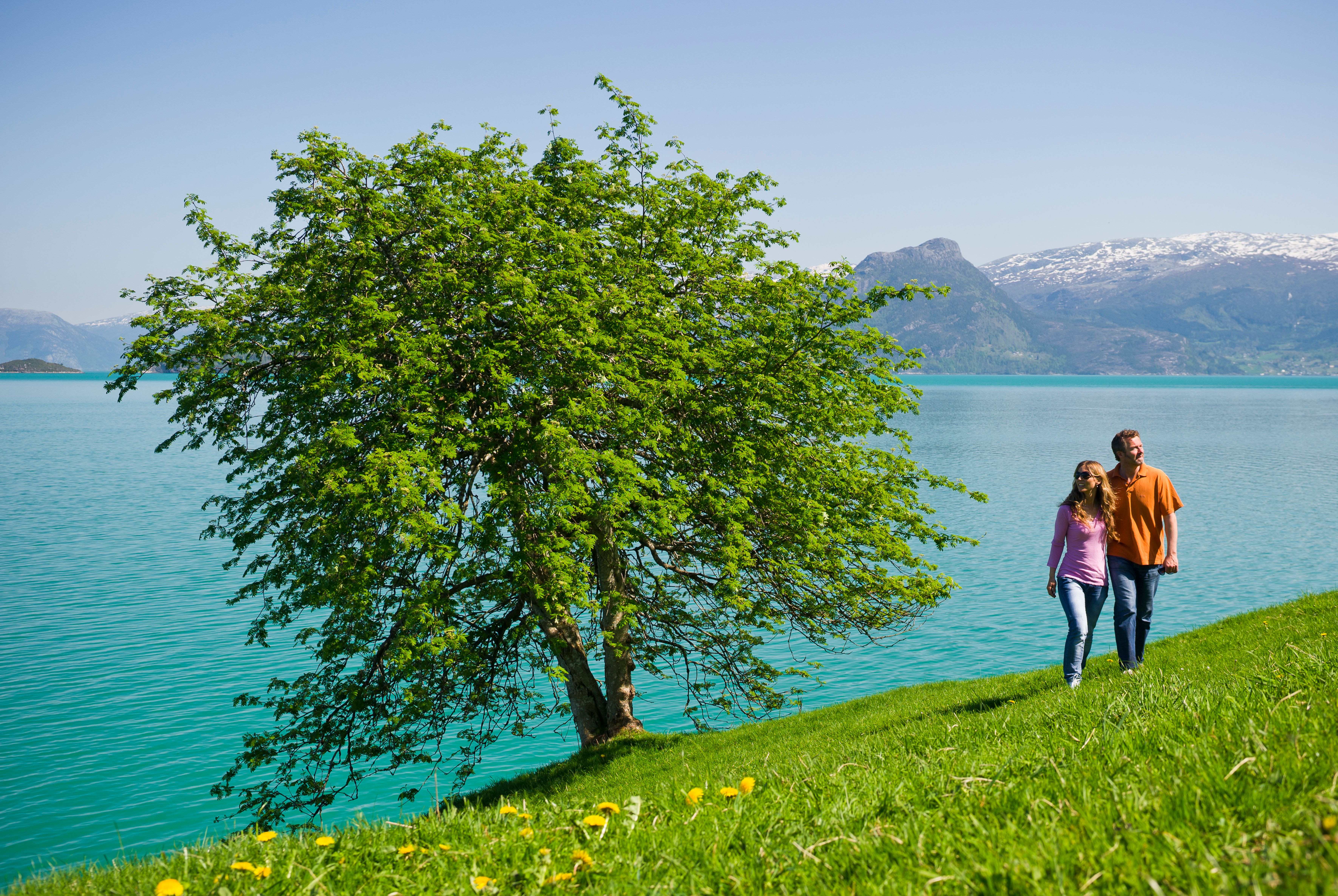 Couple walking by the Hardangerfjord near Oddland Camping on a sunny day.