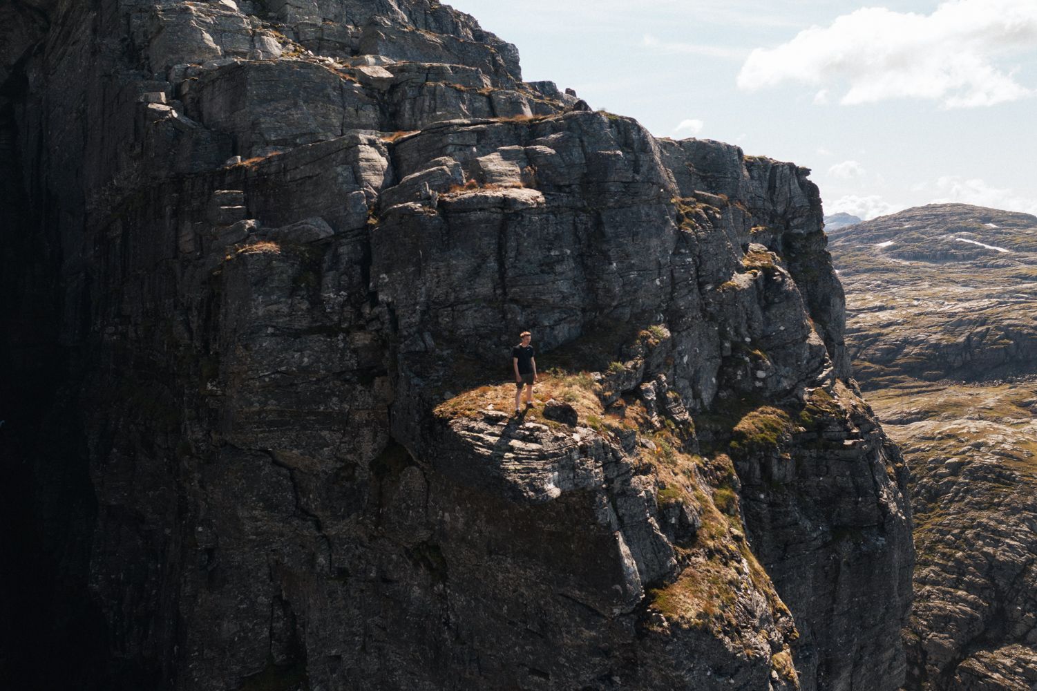 Person står på fjellformasjon og ser utover fjellandskapet.