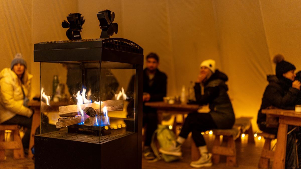 Guests gathered around the fire inside a lavvu during a cultural experience at Tromsø Lapland.