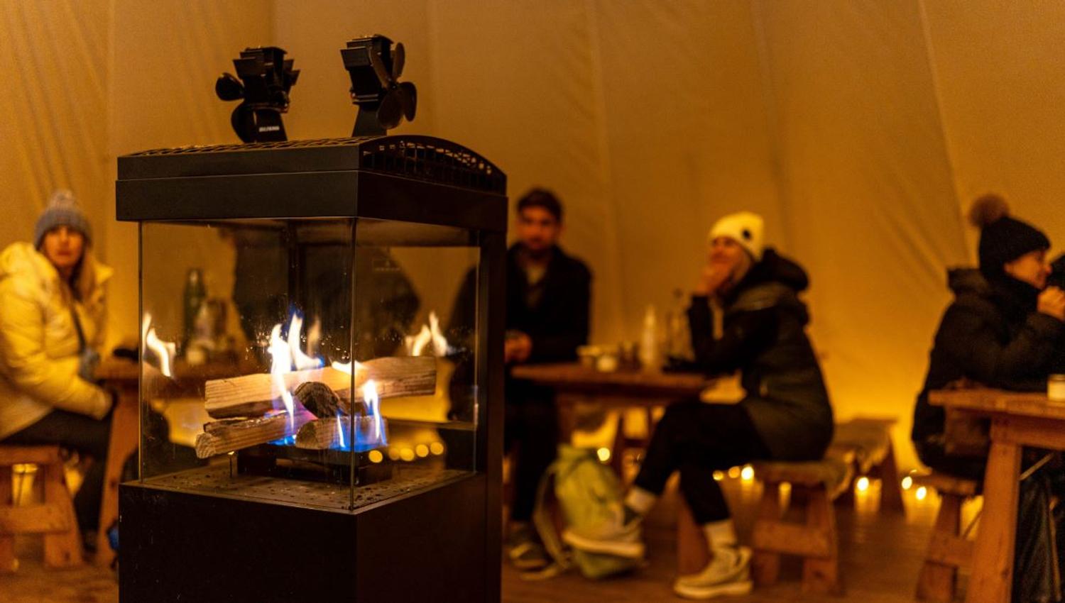 Guests gathered around the fire inside a lavvu during a Sámi cultural experience at Tromsø Lapland.