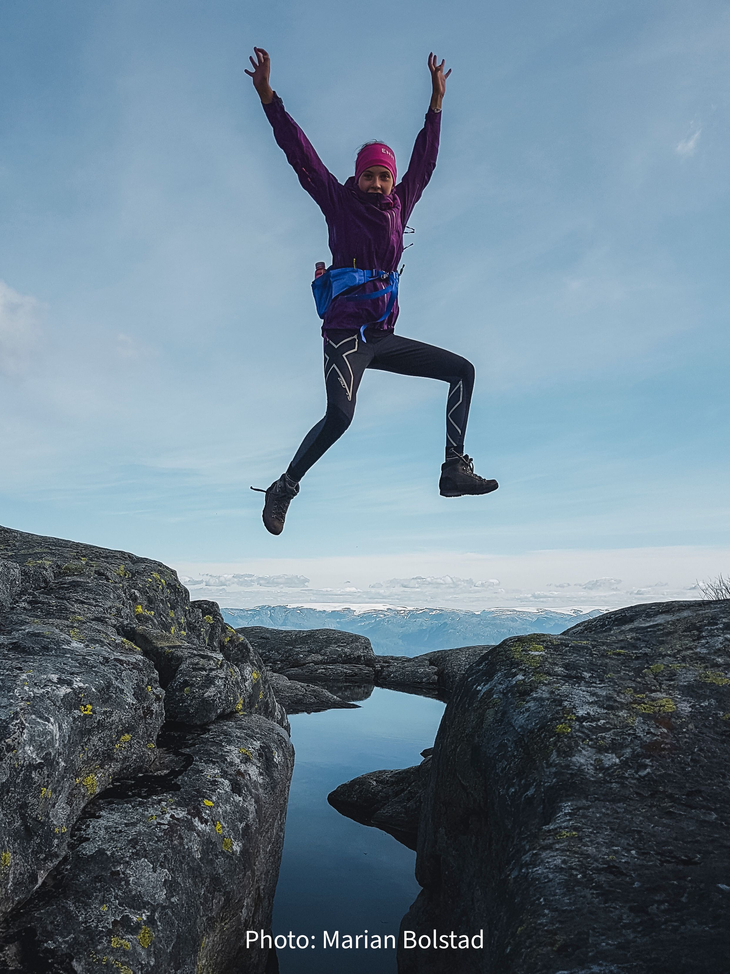 Person jumping across a mountain pond in Hardanger, Norway, capturing joy and outdoor adventure