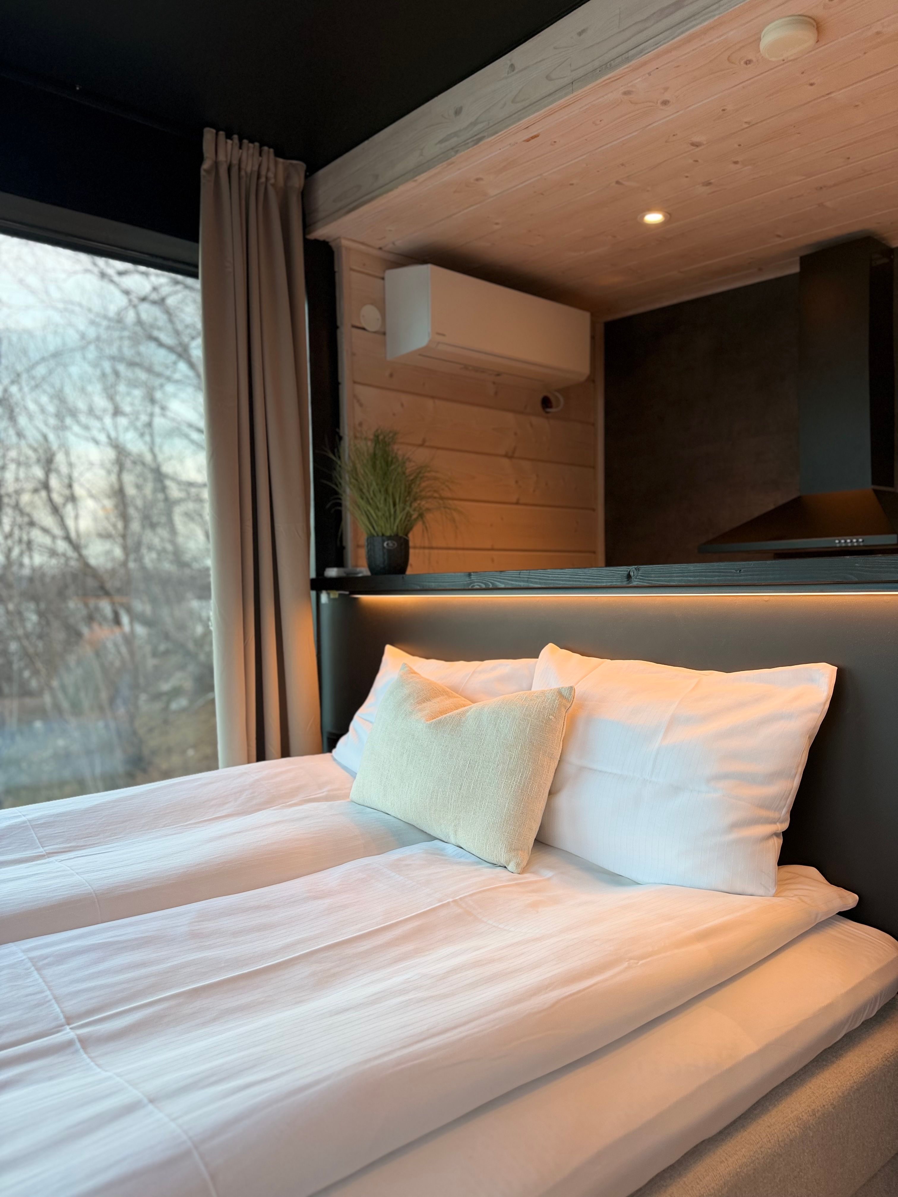 Een comfortabel bed met witte lakens en een kussen, met uitzicht op buiten.