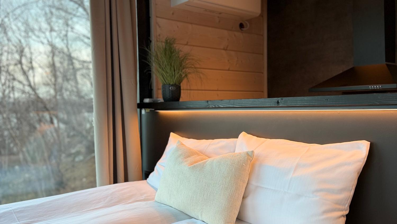 Een comfortabel bed met witte lakens en een kussen, met uitzicht op buiten.