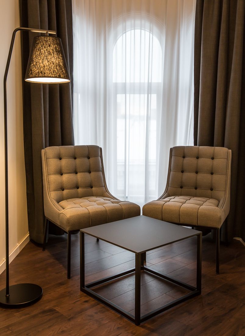 Two brown chairs, coffee table and lamp in front of a window. Saga Hotel & Poshtel Oslo Central. Photo