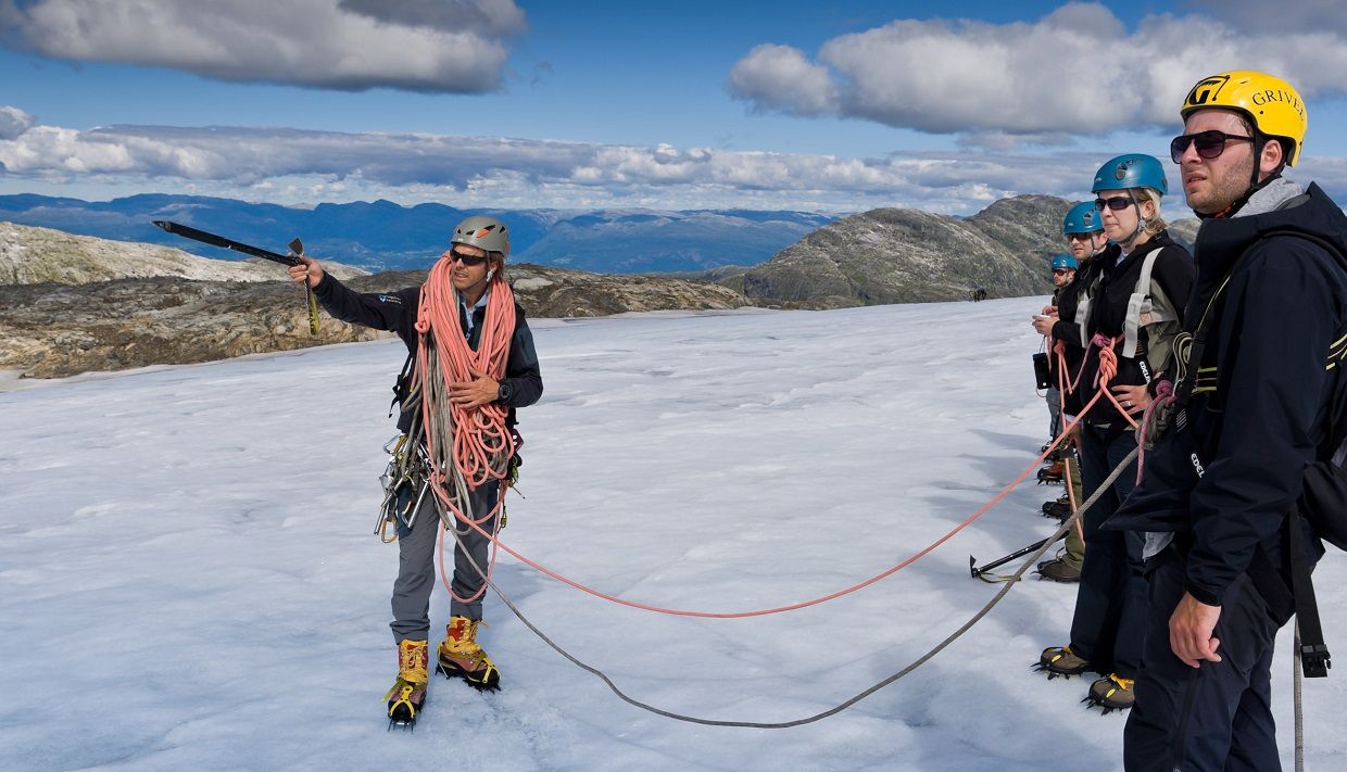A glacier guide instructs a group of hikers in safety techniques on the Folgefonna Glacier.