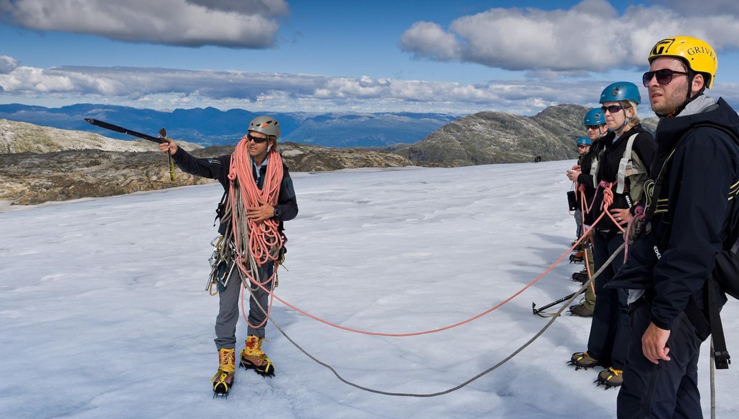 A glacier guide instructs a group of hikers in safety techniques on the Folgefonna Glacier.