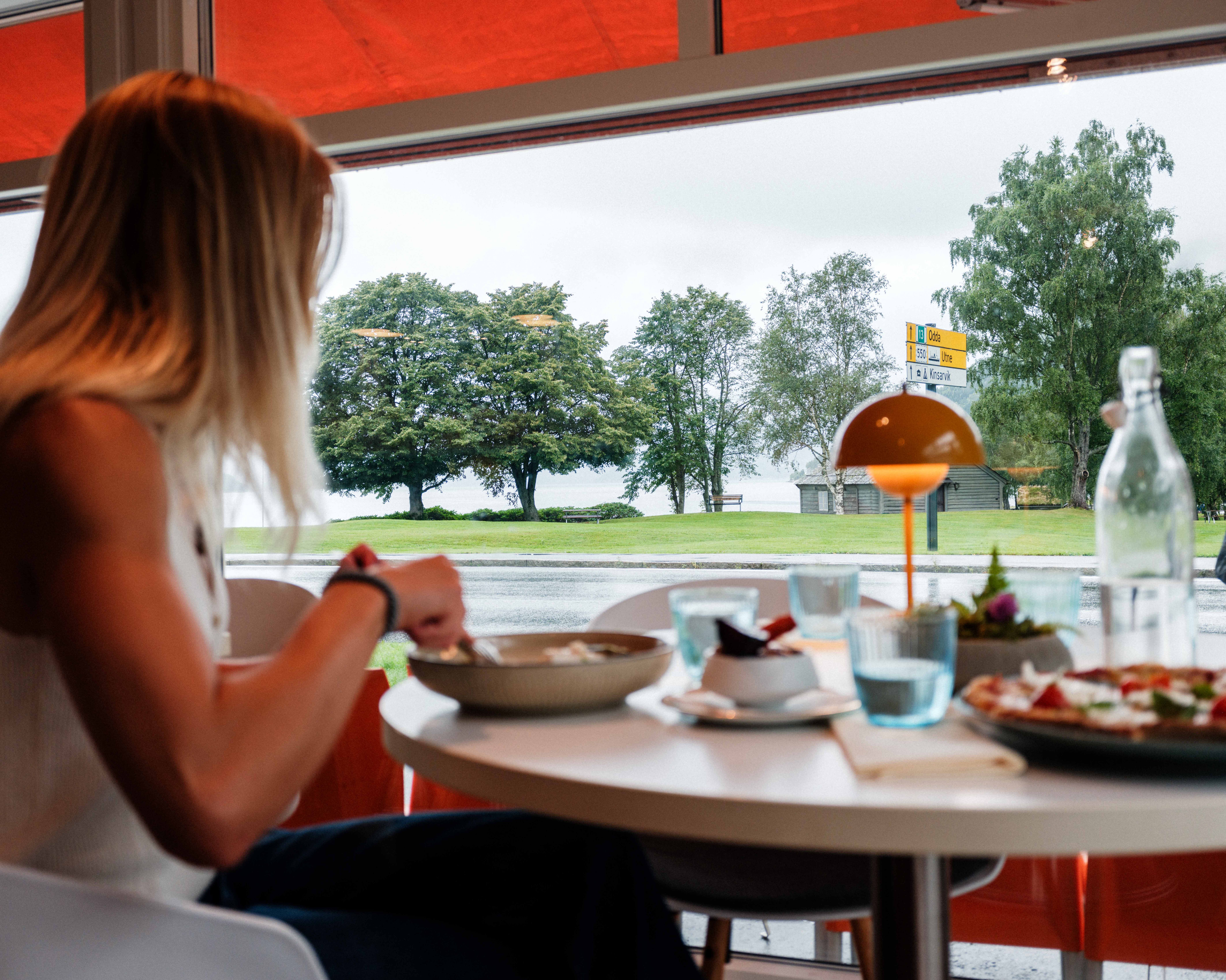 A guest enjoys lunch with fjord views at Gløyp Spiseri in Kinsarvik.