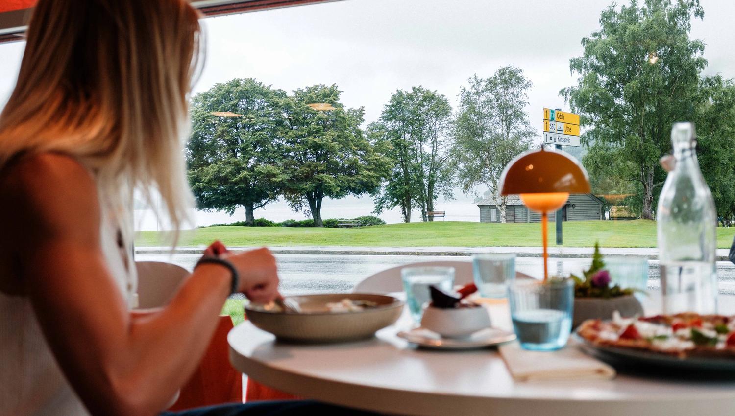 A guest enjoys lunch with fjord views at Gløyp Spiseri in Kinsarvik.