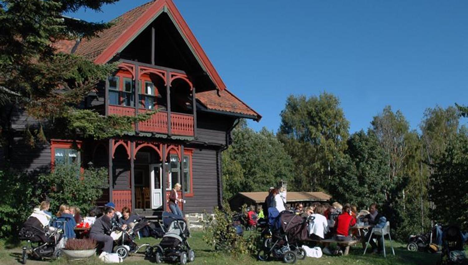 Mennesker som sitter foran et gammelt trehus.