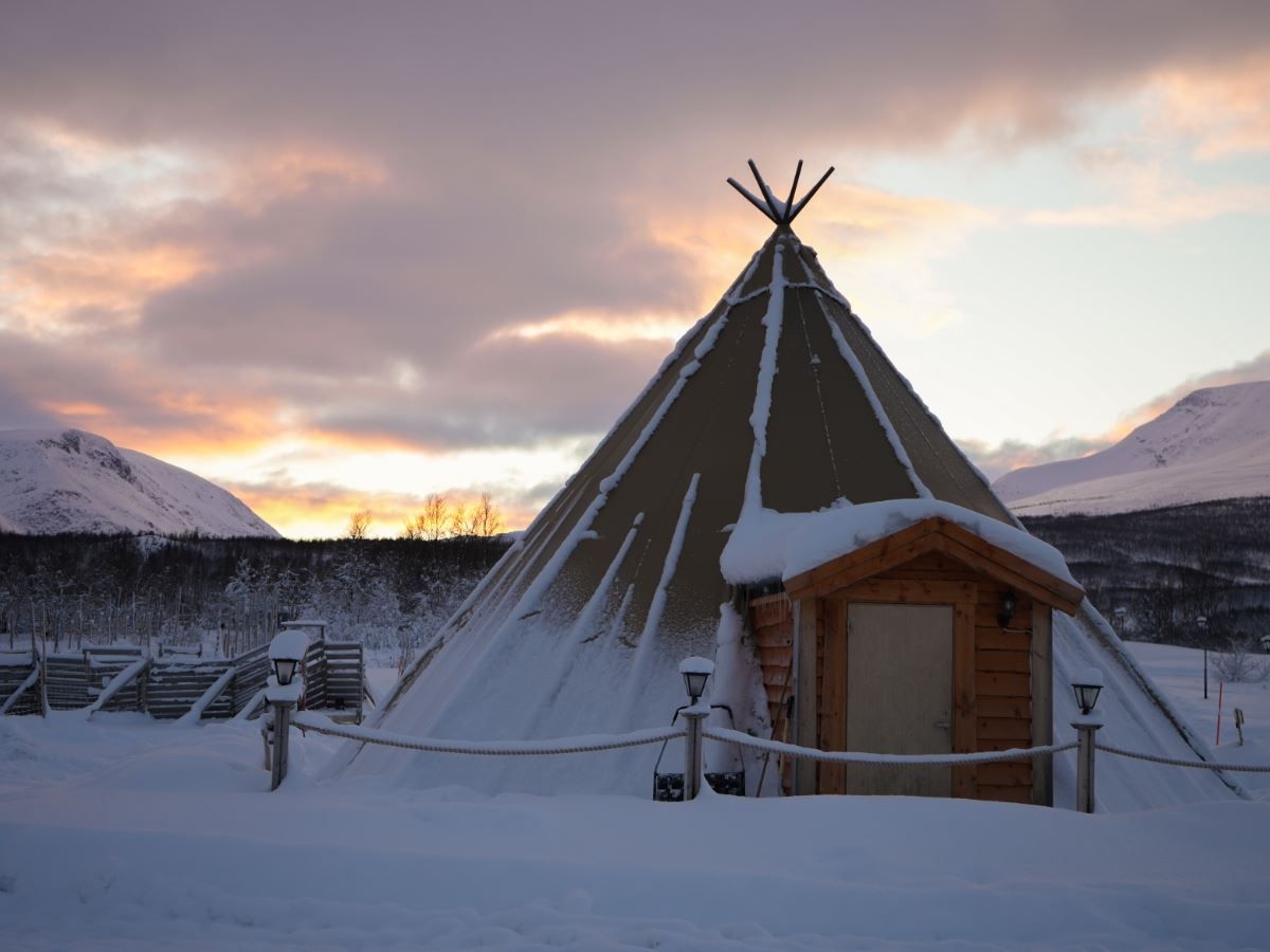 Traditional lavvu at Tromsø Lapland’s Sámi camp surrounded by snow and mountains.