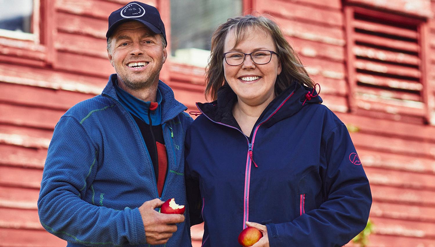 Hosts of Helleland Gard, smiling with fresh apples from the farm.