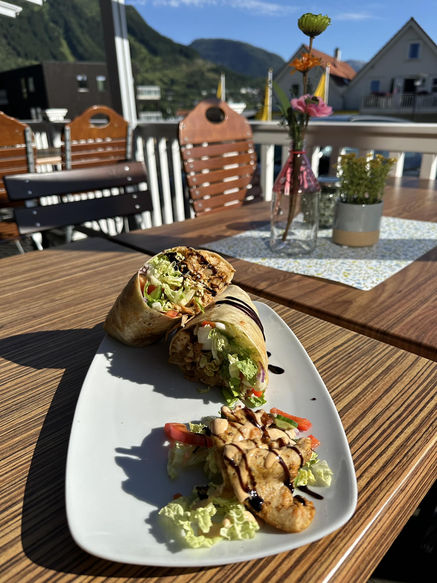Nydeleg wrap og grilla kylling servert på terrassen til Gjøa Sjømat, med utsikt mot fjell og fjord i Rosendal.