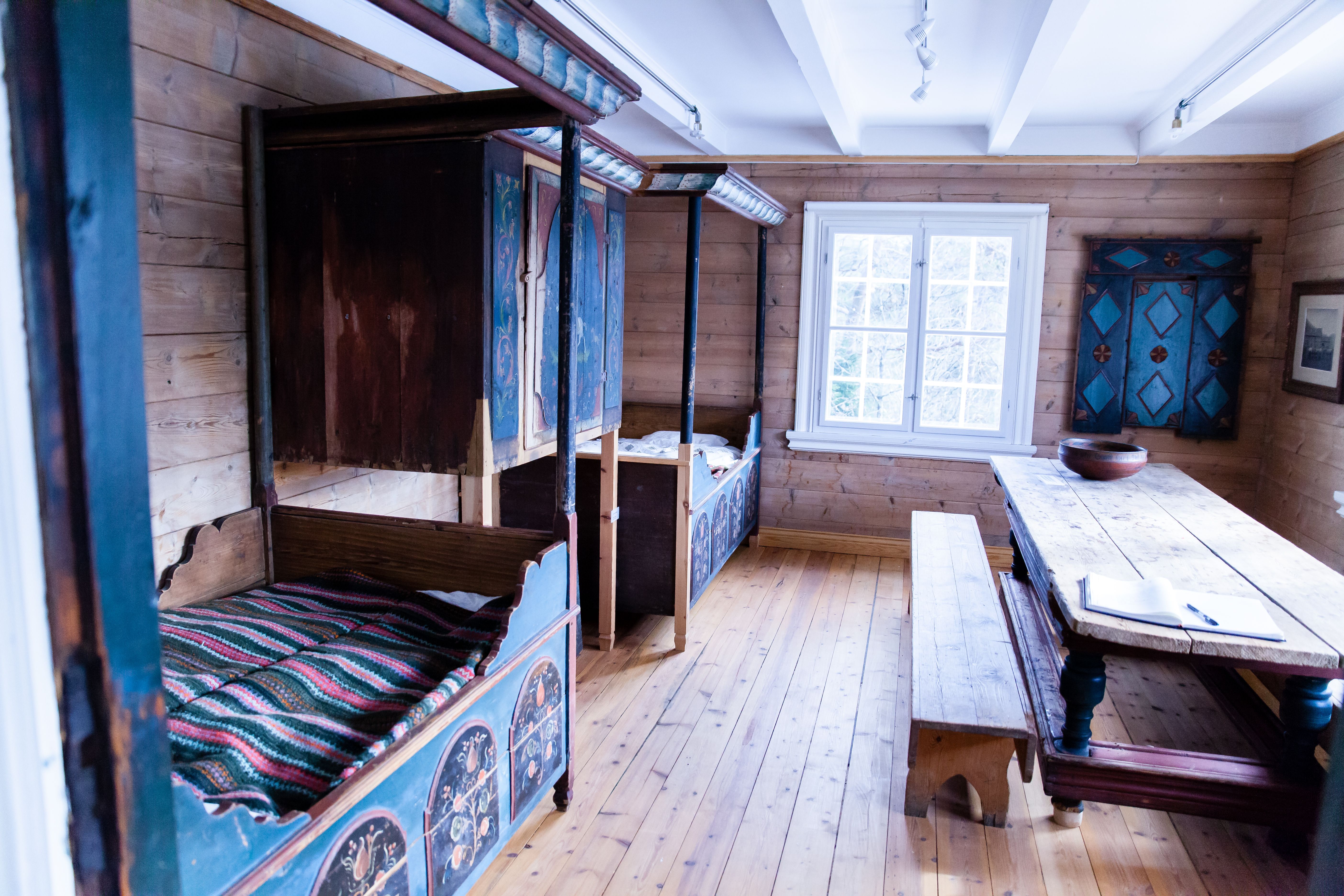 Marnardal Museum and Mjålandsstova, two beds with an overhead cabinet in the middle. Painted in blue with decorative details. Large table with benches