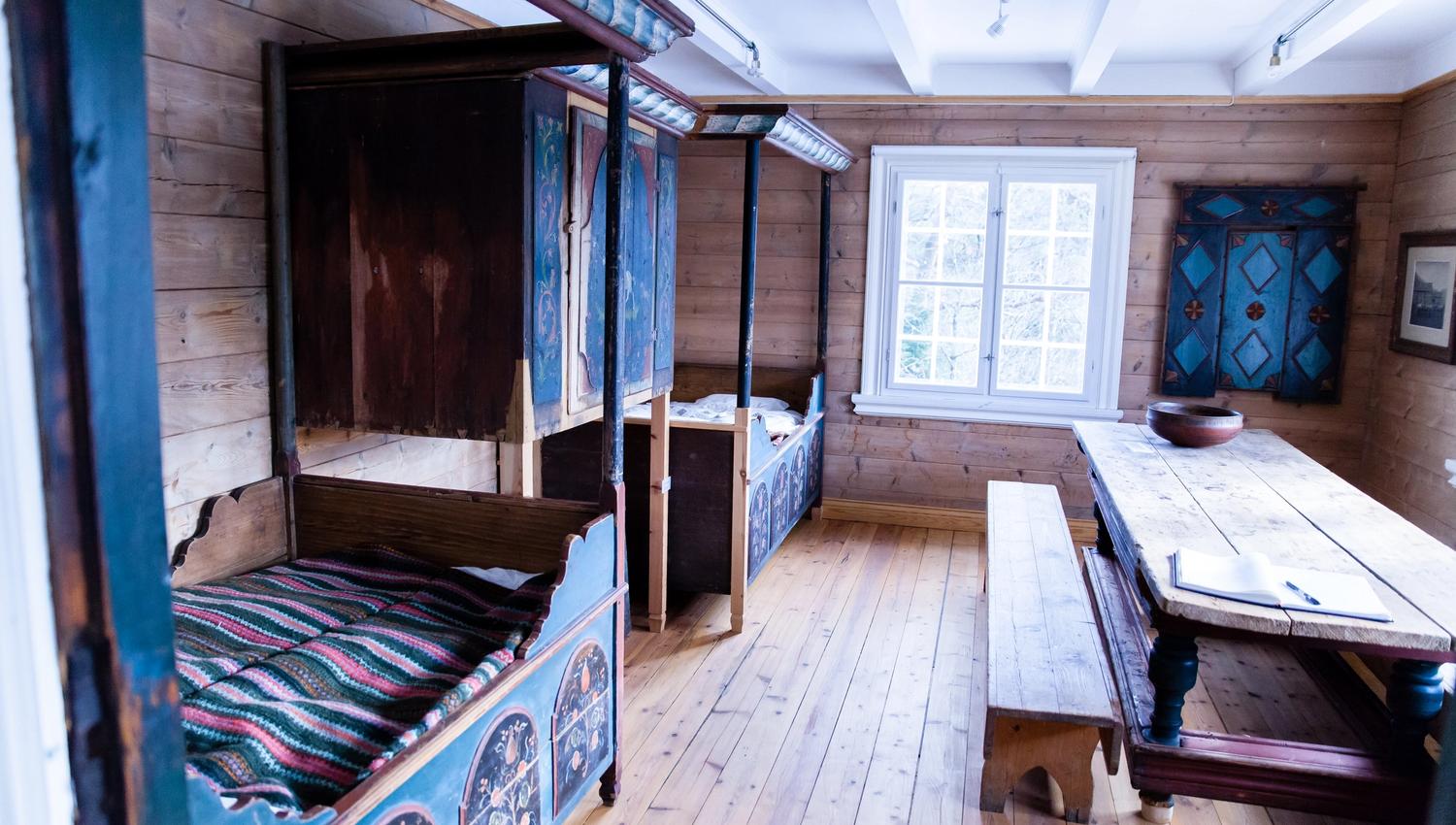 Marnardal Museum and Mjålandsstova, two beds with an overhead cabinet in the middle. Painted in blue with decorative details. Large table with benches