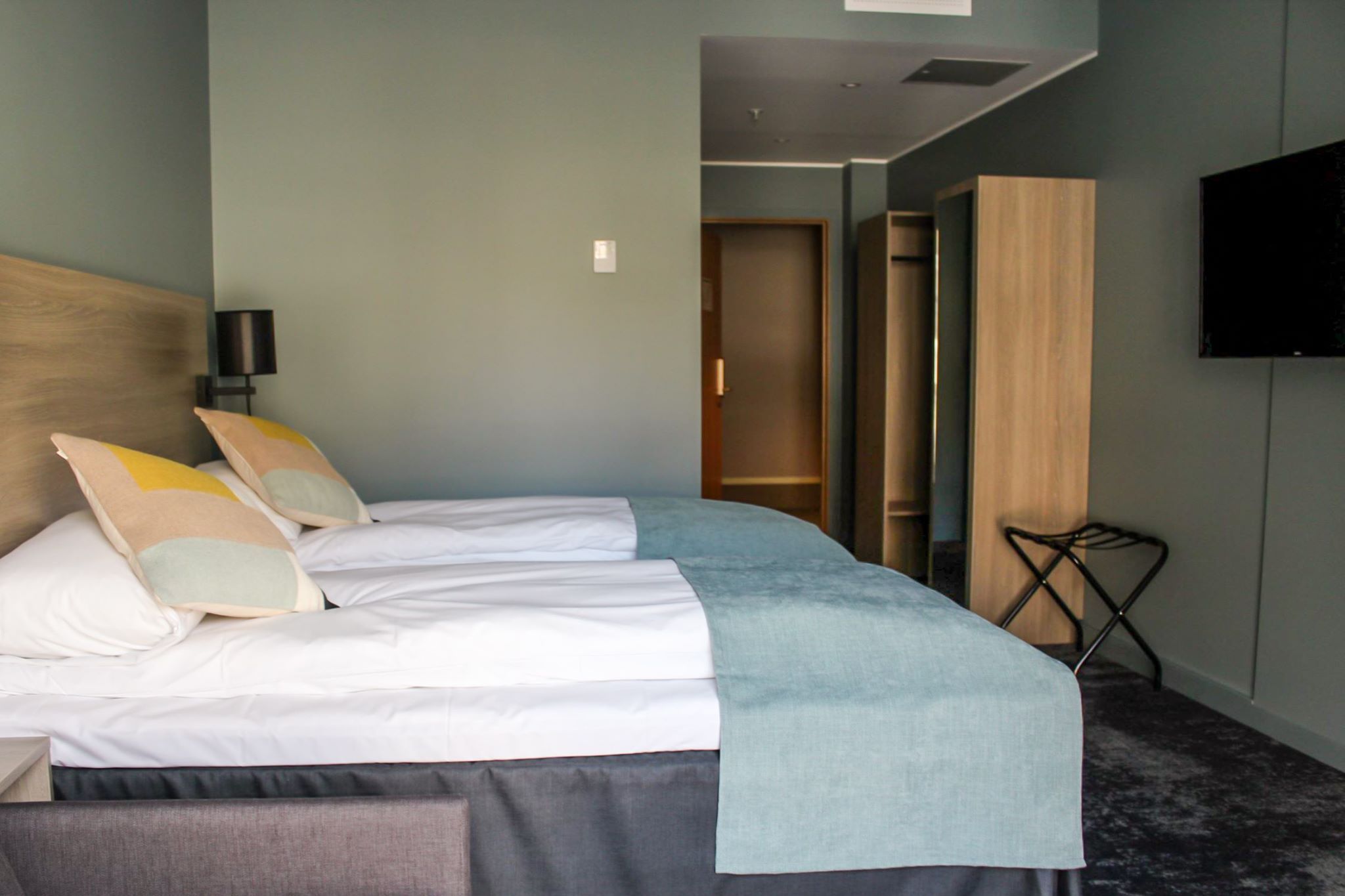 Standard hotel room with twin beds, TV, and convenient storage.