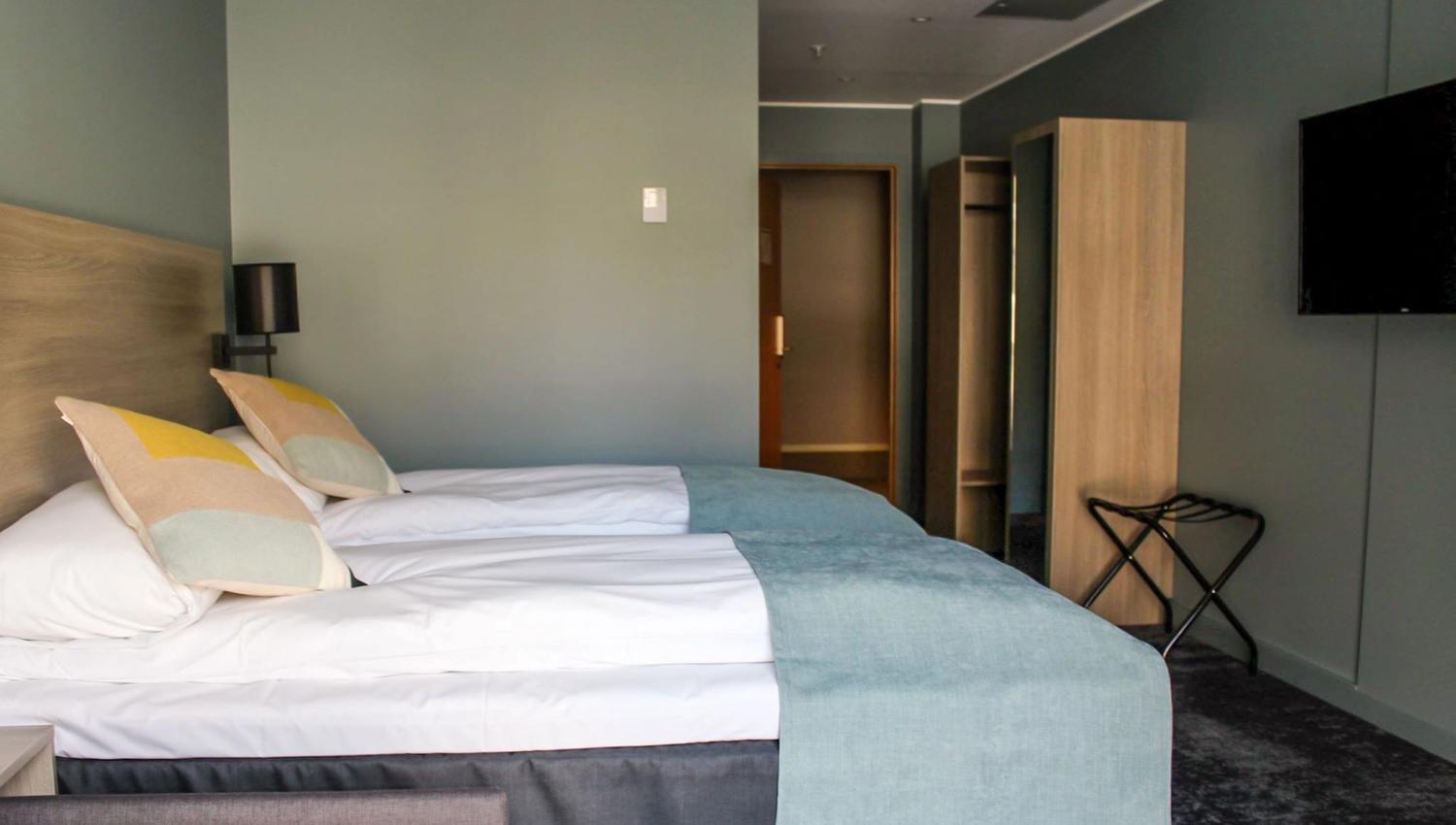 Standard hotel room with twin beds, TV, and convenient storage.