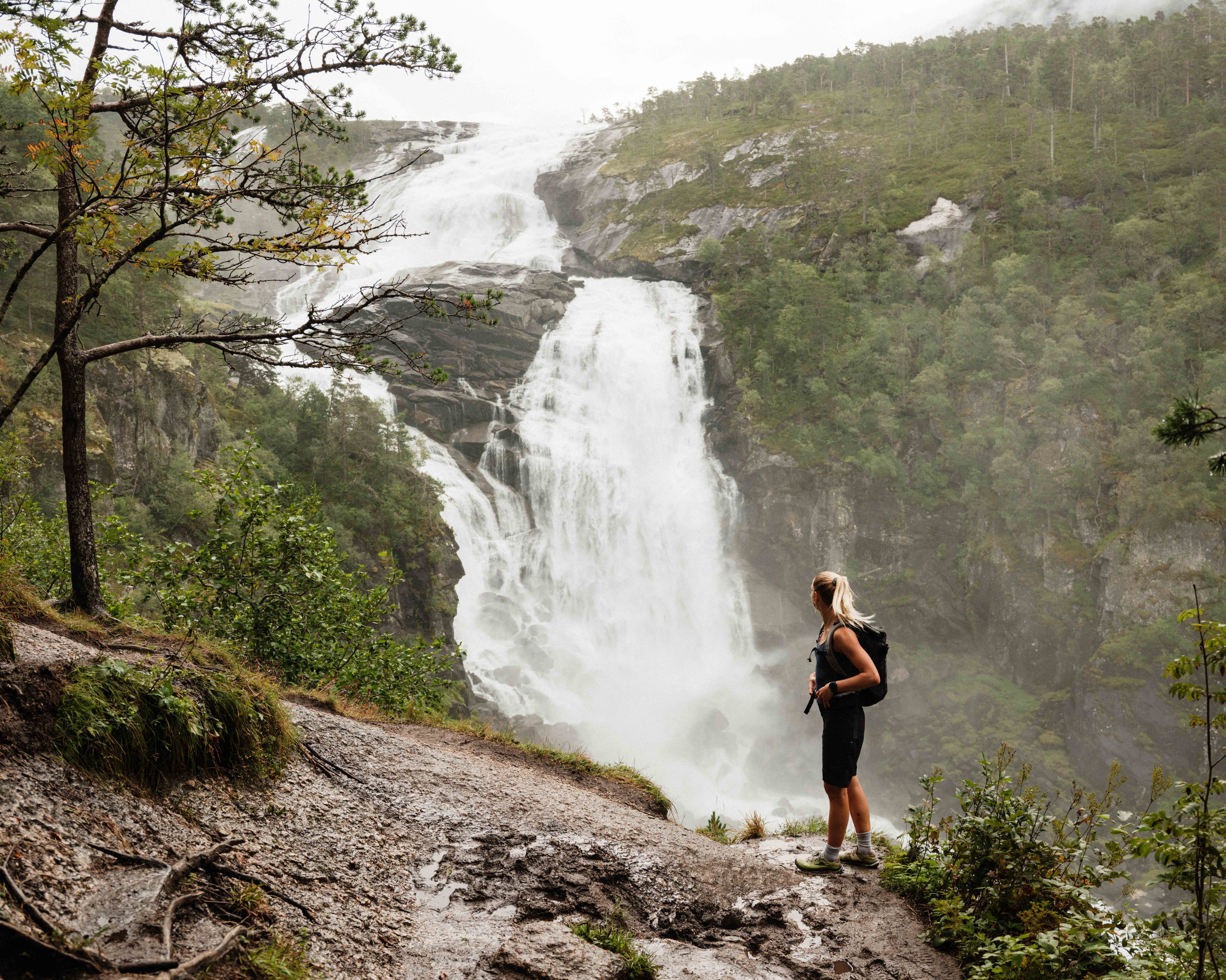 Hiker admiring Nyastølsfossen, one of the four spectacular waterfalls in Husedalen.