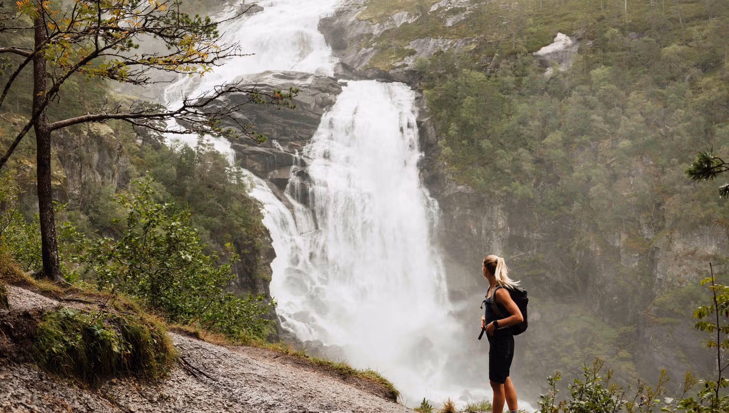 Hiker admiring Nyastølsfossen, one of the four spectacular waterfalls in Husedalen.