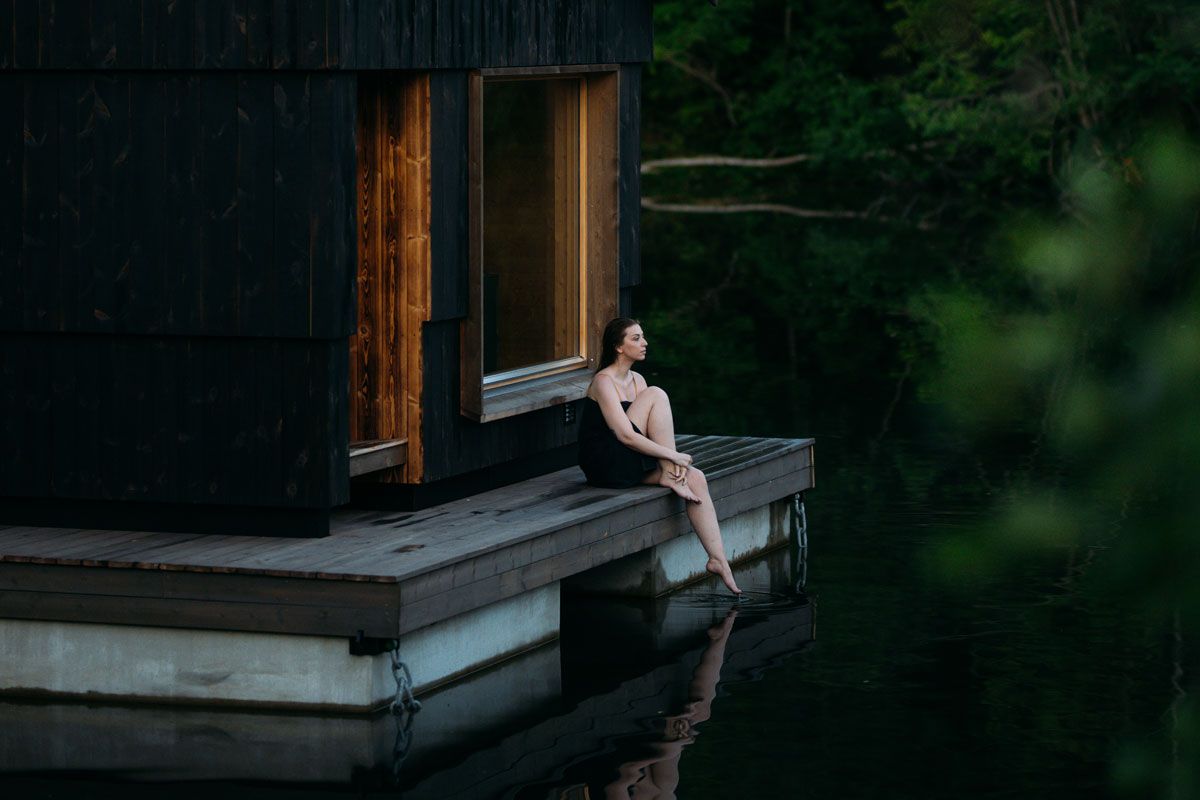 A lady is sitting outside the sauna of Skogens rom