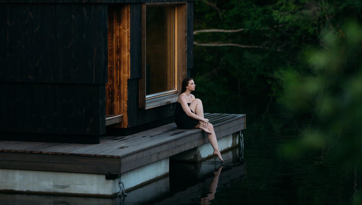 A lady is sitting outside the sauna of Skogens rom