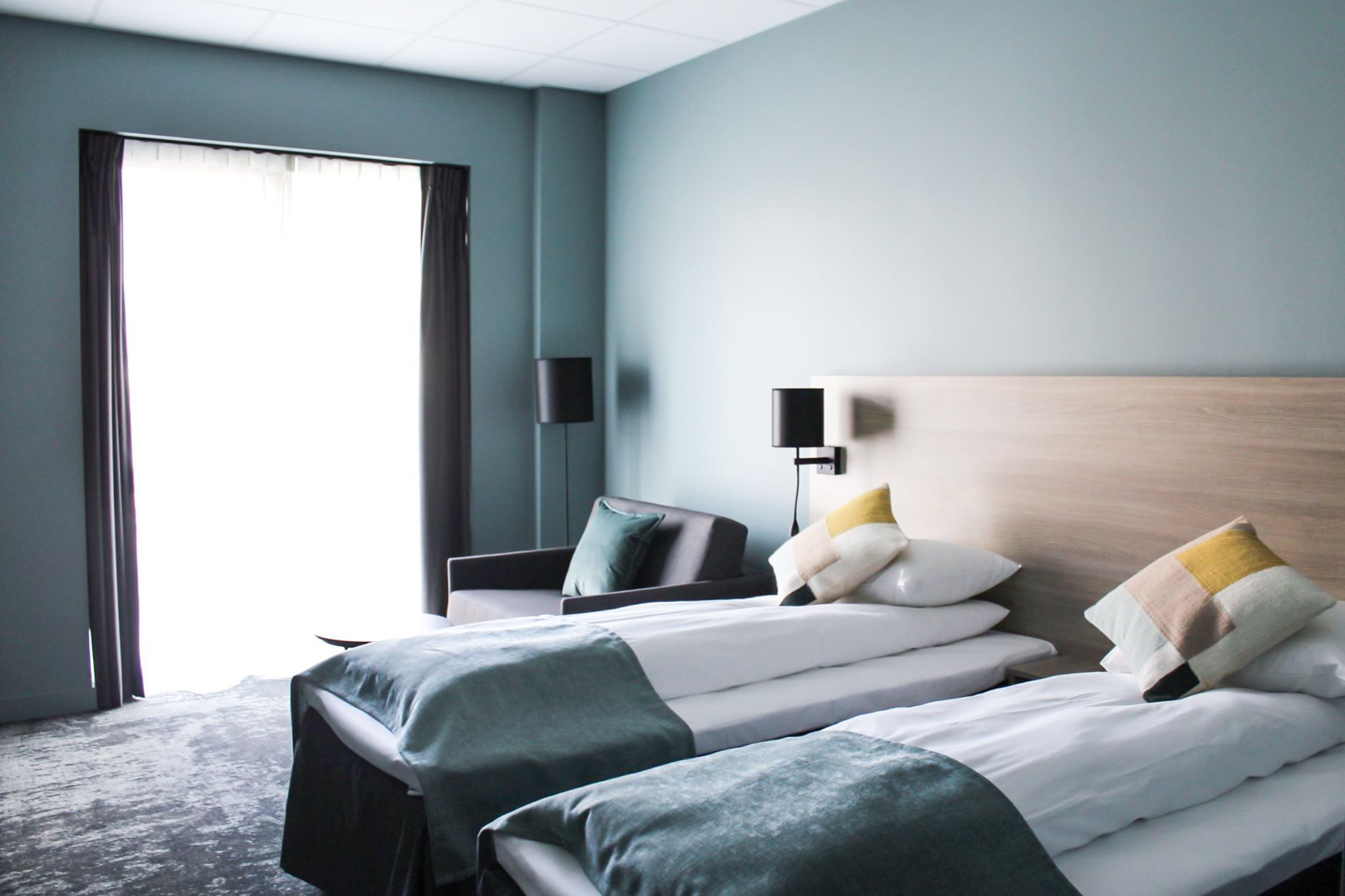 Bright hotel room with two single beds and modern furnishings.