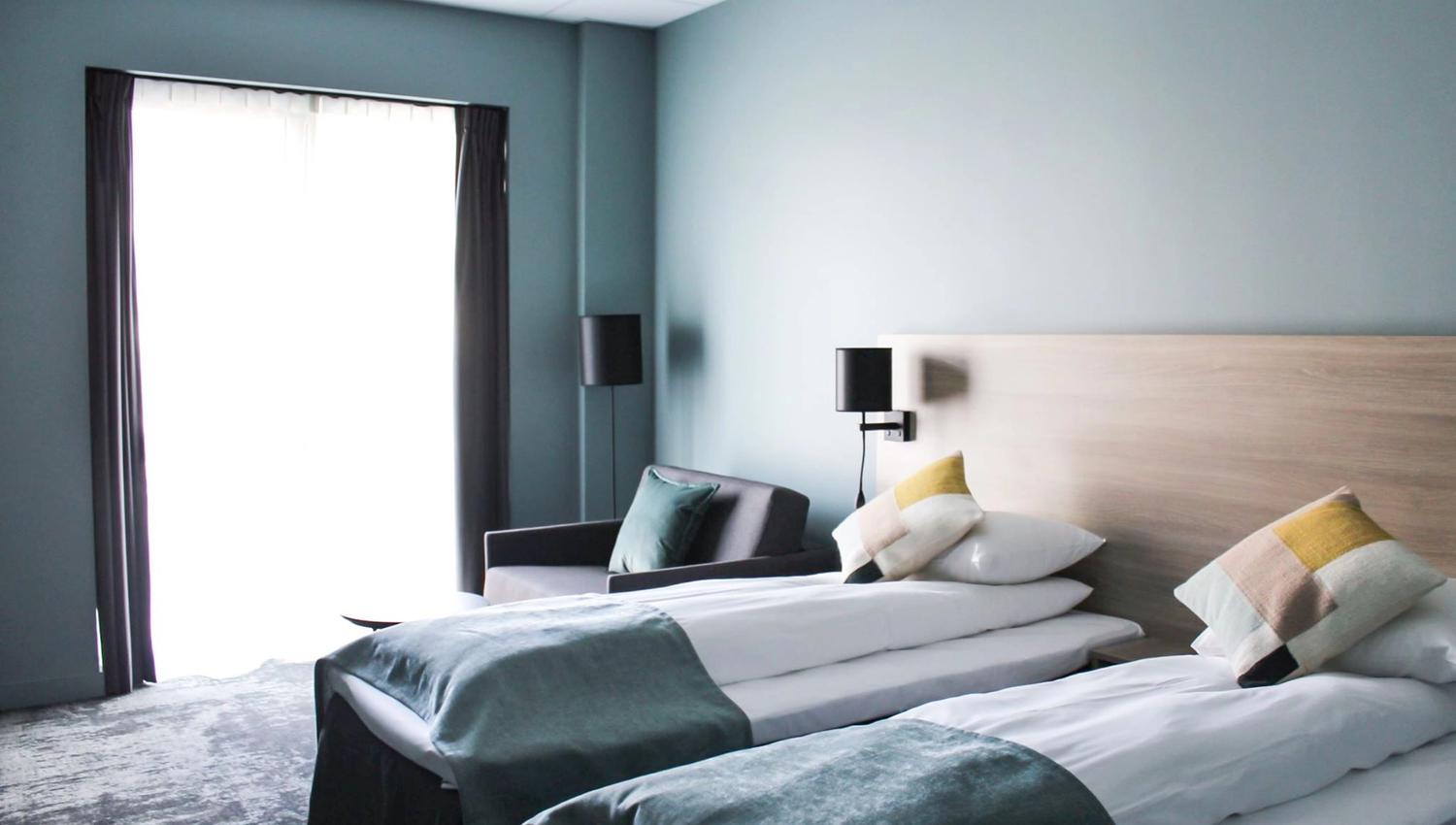 Bright hotel room with two single beds and modern furnishings.