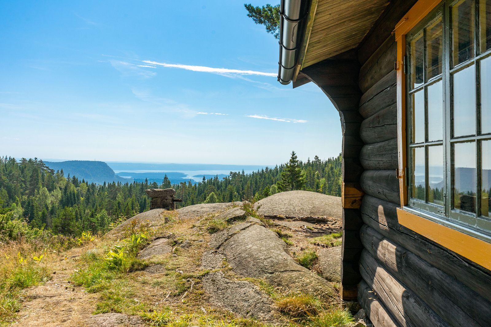 Brun hytte med utsikt over sjø og fjell