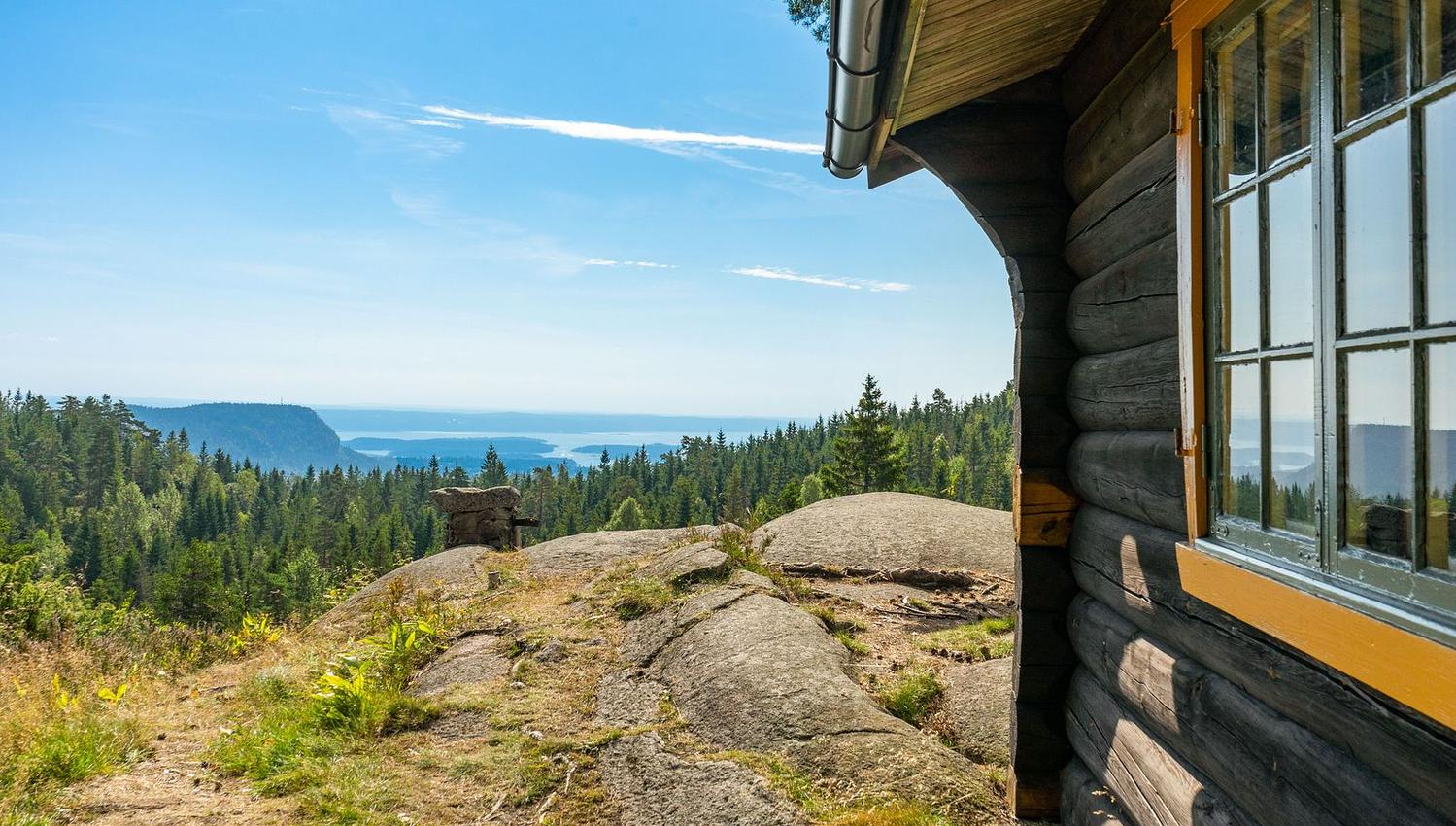 Brun hytte med utsikt over sjø og fjell