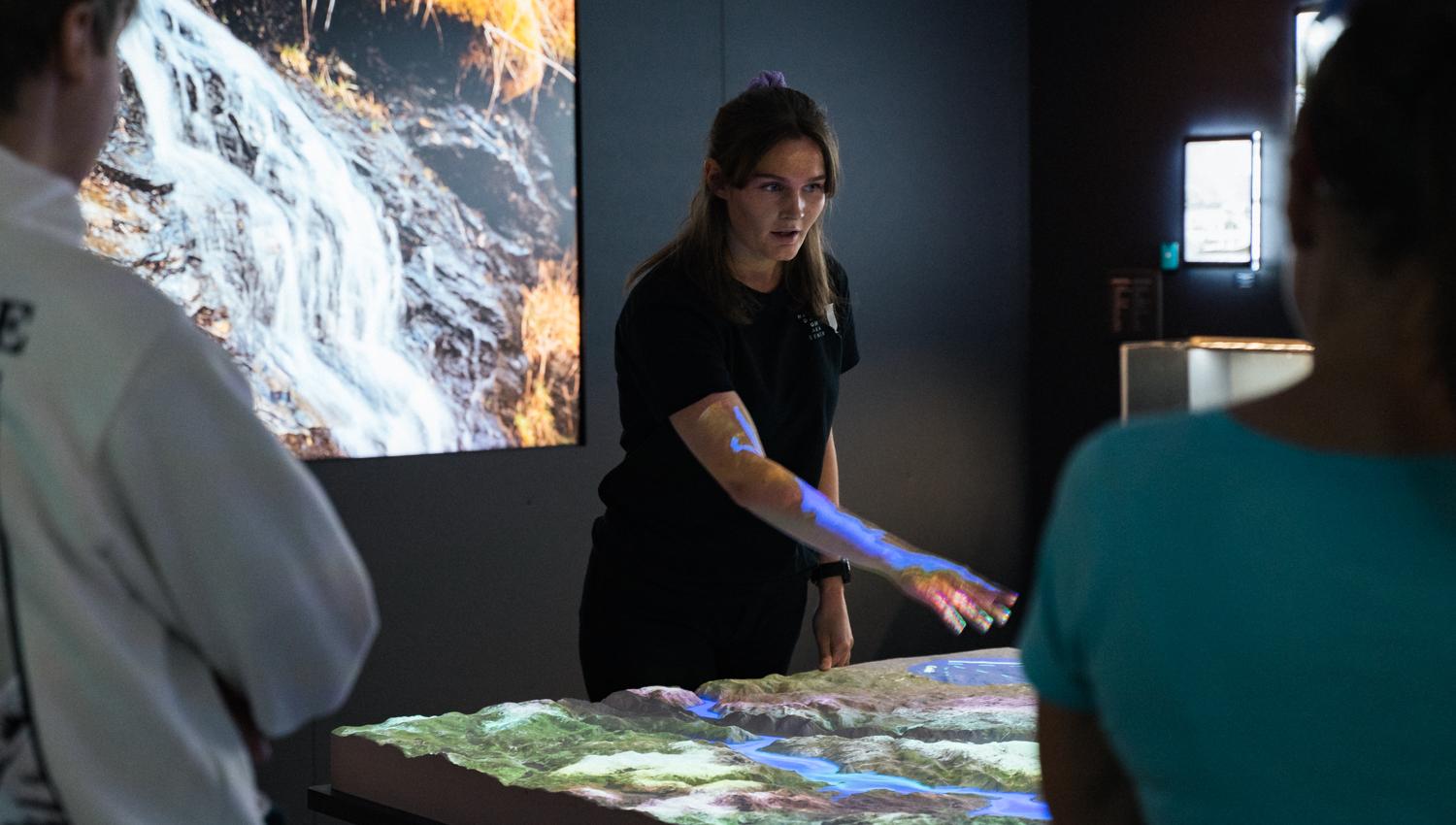 Guide presenting an interactive terrain map in the “This is where we live” exhibition at Hardanger Aquaculture Centre.