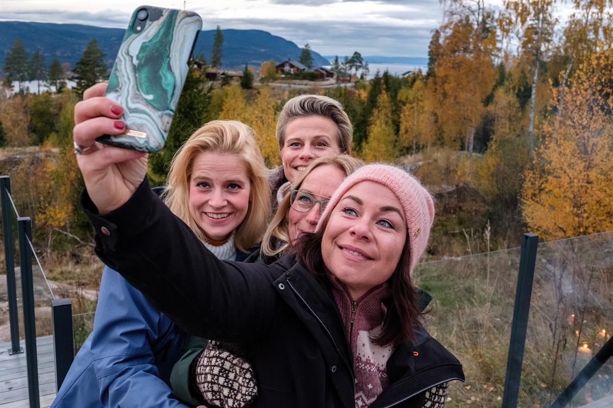 People taking a selfie in a forest area with autumn colors.
