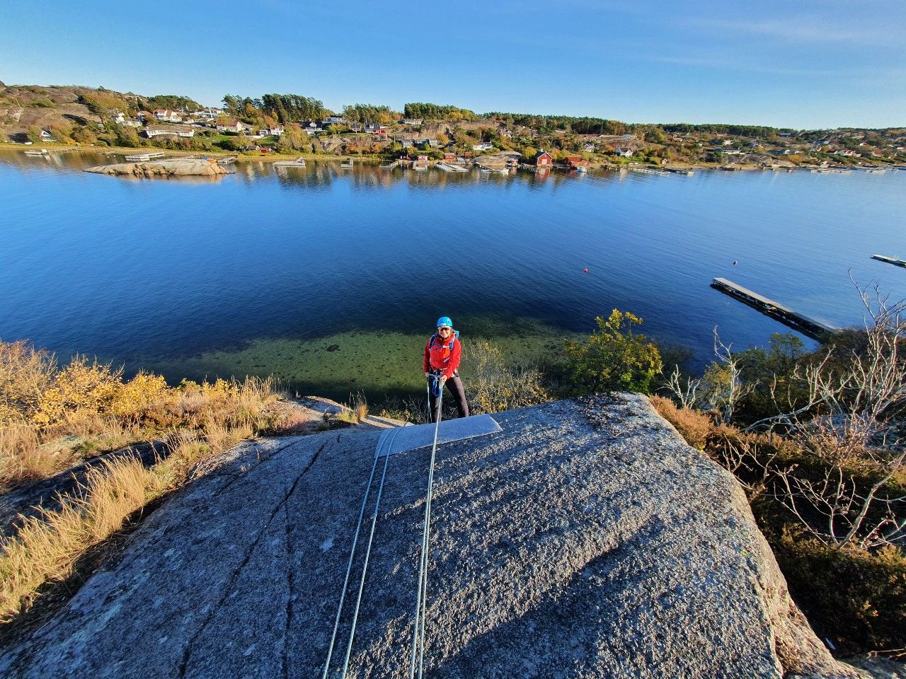 Fantastisk utsikt utover skjærgården mens en jente rappellerer ned fjellet