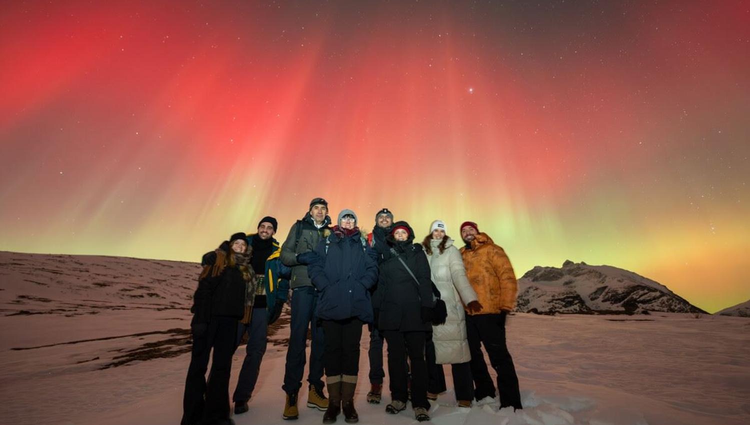 Red Nortern Lights appear behind a group of guests