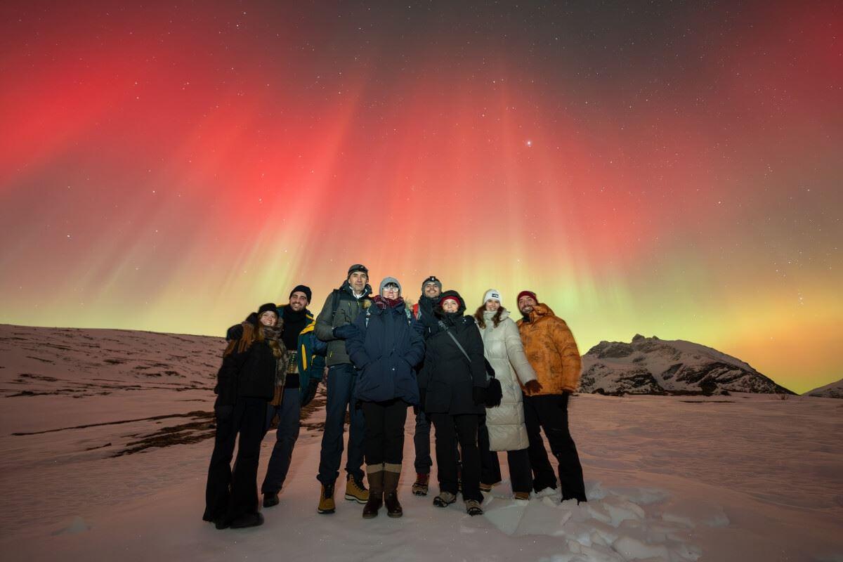 Red Nortern Lights appear behind a group of guests